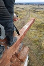 woodworker with a chainsaw makes drank on a wooden beam construction of houses