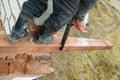 woodworker with a chainsaw makes drank on a wooden beam construction of houses