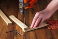 Woodworker hammers a nail into a plank with a hammer. Hands of the master close-up. Working environment in a carpentry workshop