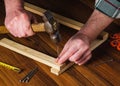 Woodworker hammers a nail into a plank with a hammer. Hands of the master close-up. Working environment in a carpentry workshop