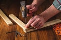 Woodworker hammers a nail into a plank with a hammer. Hands of the master close-up. Working environment in a carpentry workshop