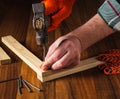 Woodworker hammers a nail into a plank with a hammer. Hands of the master close-up. Working environment in a carpentry workshop Royalty Free Stock Photo