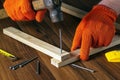 Woodworker hammers a nail into a plank with a hammer. Hands in work gloves of the master close-up. Working environment in a Royalty Free Stock Photo