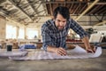 Woodworker leaning on a bench in his workshop reading blueprints Royalty Free Stock Photo