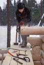 Woodworker makes groove at end logs using chainsaws.