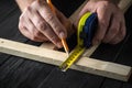 Woodworker makes pencil marks on a block of wood. Hands of the master close-up at work. Working environment in a carpentry