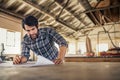 Woodworker reading furniture design plans on a workshop bench Royalty Free Stock Photo