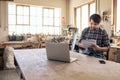 Woodworker reading notes and using a laptop in his workshop