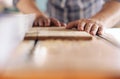 Woodworker sawing a plank of wood in his carpentry workshop