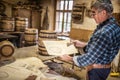 Woodworker shows drawing, according to which wooden barrels are to be built in a vintage workshop