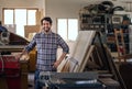 Woodworker smiling while standing by equipment in his workshop