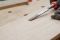 Woodworker using chisel cuts slot on wooden board close up