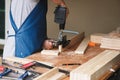 Woodworking entrepreneurs are using a drill through the wood holes to assemble and build wooden tables for customers