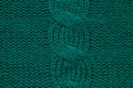 Wool hand-knitted or machine knitting pattern with braids. Knit warm green sweater or scarf. Cozy dark emerald blanket