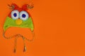 Wool knitted handmade hat for children in the form of an owl on an orange background. Copy space for text Royalty Free Stock Photo