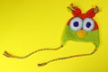 Wool knitted handmade hat for children in the form of an owl on a yellow background. Copy space for text Royalty Free Stock Photo