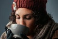 Woolen-clad woman savors latte, vivid eyes shining