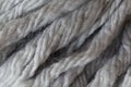 Woolen fluffy threads or tassels from scarf, macro. Soft grey merino wool backdrop, closeup. Autumn and winter flat lay.