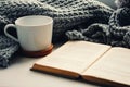 Woolen scarf, a cup of tea and book on the windowsill. Hygge and cozy autumn concept