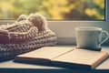 Woolen scarf, a cup of tea and book on the windowsill. Hygge and cozy autumn concept Royalty Free Stock Photo