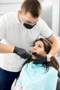 Wooman in dental chair, dentist pinches her tooth with forceps