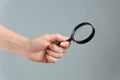 Wooman hand holding magnifyer glass on gray background Royalty Free Stock Photo