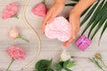 Wooman`s hands holding a gift box on gray wooden background with beautiful flowers and green leavs. Royalty Free Stock Photo