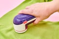 A wooman using Fabric shaver removes fabric pills from garments. Close-up, selective focus Royalty Free Stock Photo