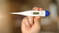 Woomen feeling sick holding a digital temperature thermometer with body temperature displayed. Testing and precautions virus Royalty Free Stock Photo