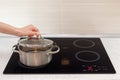 Woomen hand open a saucepan in modern kitchen with induction stove. Royalty Free Stock Photo