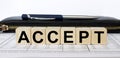 A word Accept written in a wooden cube with a pen and wallet