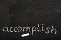 The word accomplish written with chalk on black stone.