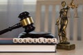 Word ACQUITTAL composed of wooden dices. Wooden gavel and statue of Themis in the background