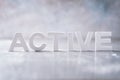 Word ACTIVE made with cement letters on grey marble background. Copy space. Business concept