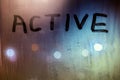 The word active written on night wet window glass close-up with bokeh background