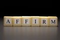 The word AFFIRM written on wooden cubes isolated on a black background