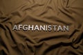 the word afghanistan laid with silver metal letters on crumpled tan khaki canvas fabric