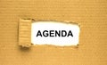 The word Agenda appearing behind torn brown paper Royalty Free Stock Photo