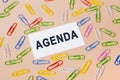 The word AGENDA written on a white business card to remind something important. Top view of business card and many colourful paper Royalty Free Stock Photo