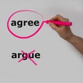 The word agree is circled with a pink pencil by a hand with a bubble, the word argue is crossed out Royalty Free Stock Photo