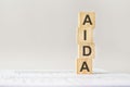 word AIDA with wood building blocks, light gray background. document with numbers on background, business concept. space
