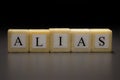 The word ALIAS written on wooden cubes isolated on a black background