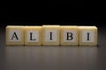 The word ALIBI written on wooden cubes isolated on a black background Royalty Free Stock Photo