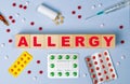 The word allergy on wooden cubes on the background of pills, syringe and ampoule