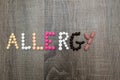 The word allergy written with pills on a wooden background.