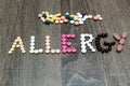 The word allergy written whith pills on a wooden background.