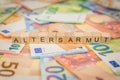 The word Altersarmut - in German for Old age poverty - written on banknotes Euro notes with wooden cube text Royalty Free Stock Photo