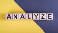 Word ANALYZE on wooden cubes on yellow - gray background