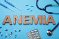 Word Anemia, pills, syringes and stethoscope on light blue background, flat lay Royalty Free Stock Photo