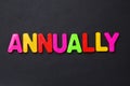 The word ANNUALLY written in letters of the children`s magnetic alphabet on a black Royalty Free Stock Photo